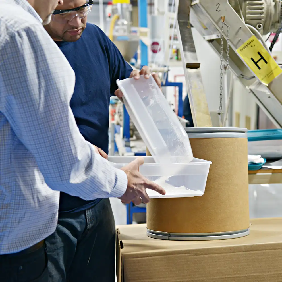 technicians-transferring-plastic-pellets-into-bin.webp